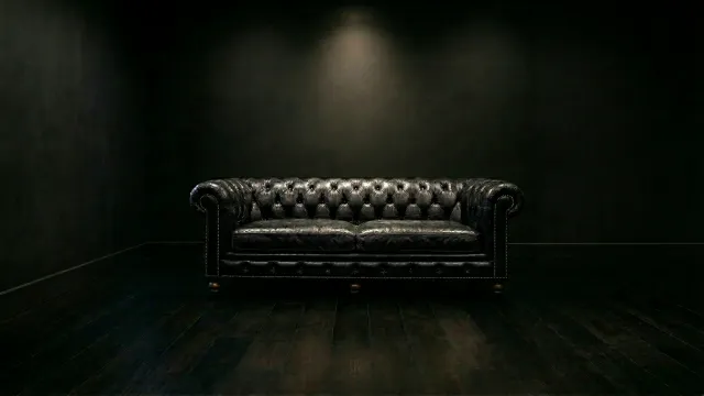 暗闇に佇む黒いチェスターフィールドソファ
