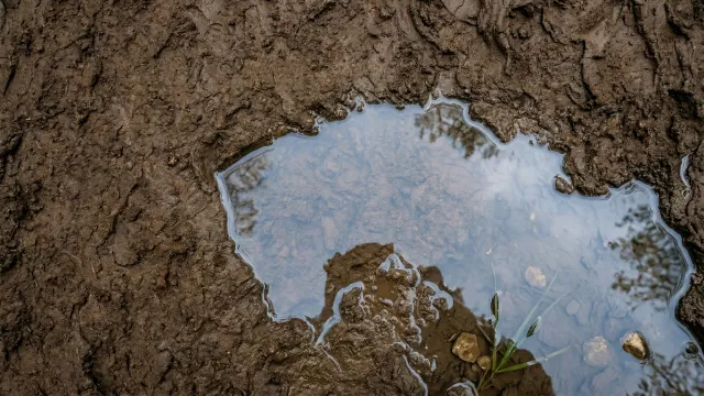 泥地に広がる澄んだ水たまりと空のリフレクション