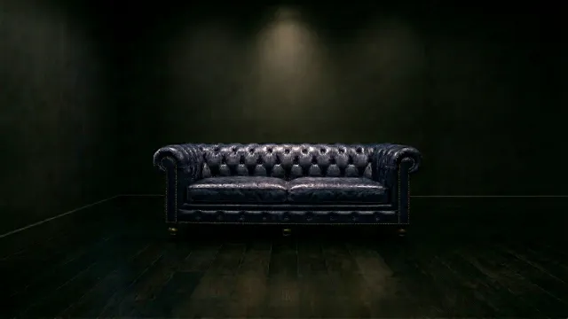 暗闇に佇むネイビーのチェスターフィールドソファ