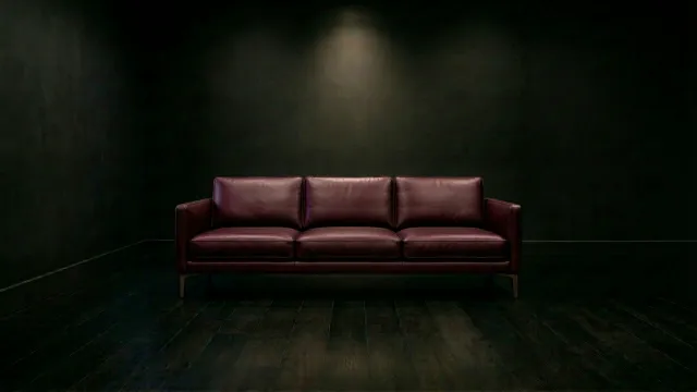 暗闇に佇むワインレッドの3シーターレザーソファ