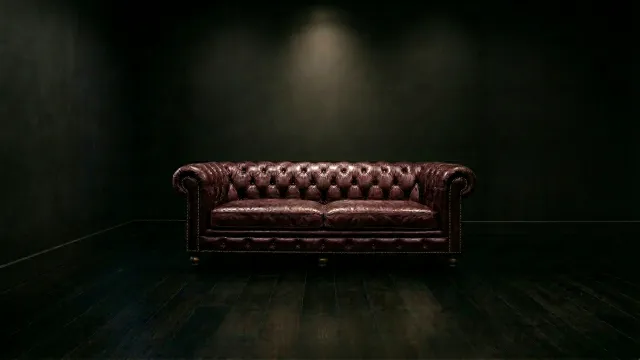 暗闇に佇むワインレッドのチェスターフィールドソファ